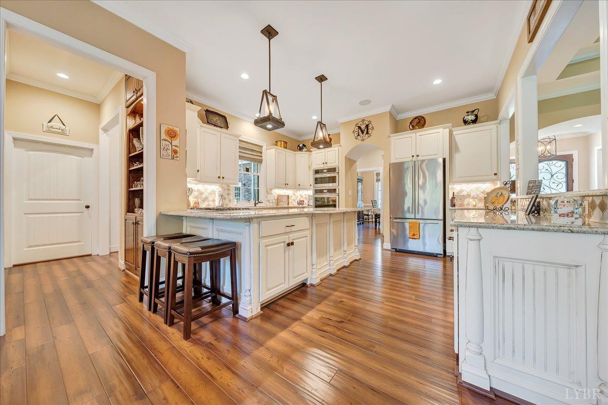 699 Police Tower Road Appomattox, VA 24522 - Photo 26 of 66 a large kitchen with stainless steel appliances kitchen island granite countertop a stove a refrigerator a sink and white cabinets with wooden floor