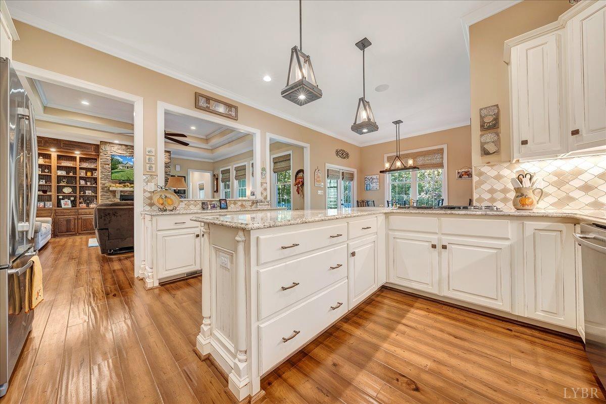 699 Police Tower Road Appomattox, VA 24522 - Photo 27 of 66 a kitchen with stainless steel appliances kitchen island granite countertop a stove a sink and white cabinets with wooden floor