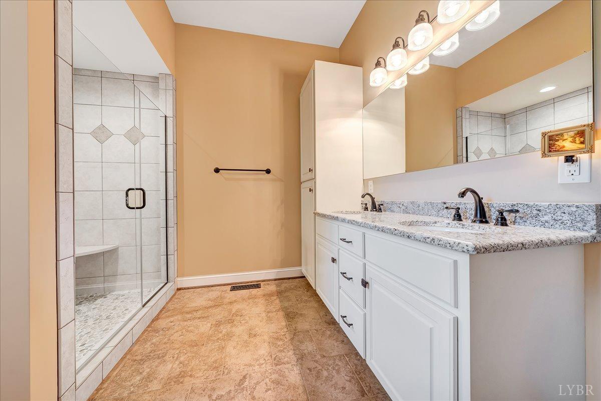 699 Police Tower Road Appomattox, VA 24522 - Photo 42 of 66 a bathroom with a granite countertop sink a mirror and shower