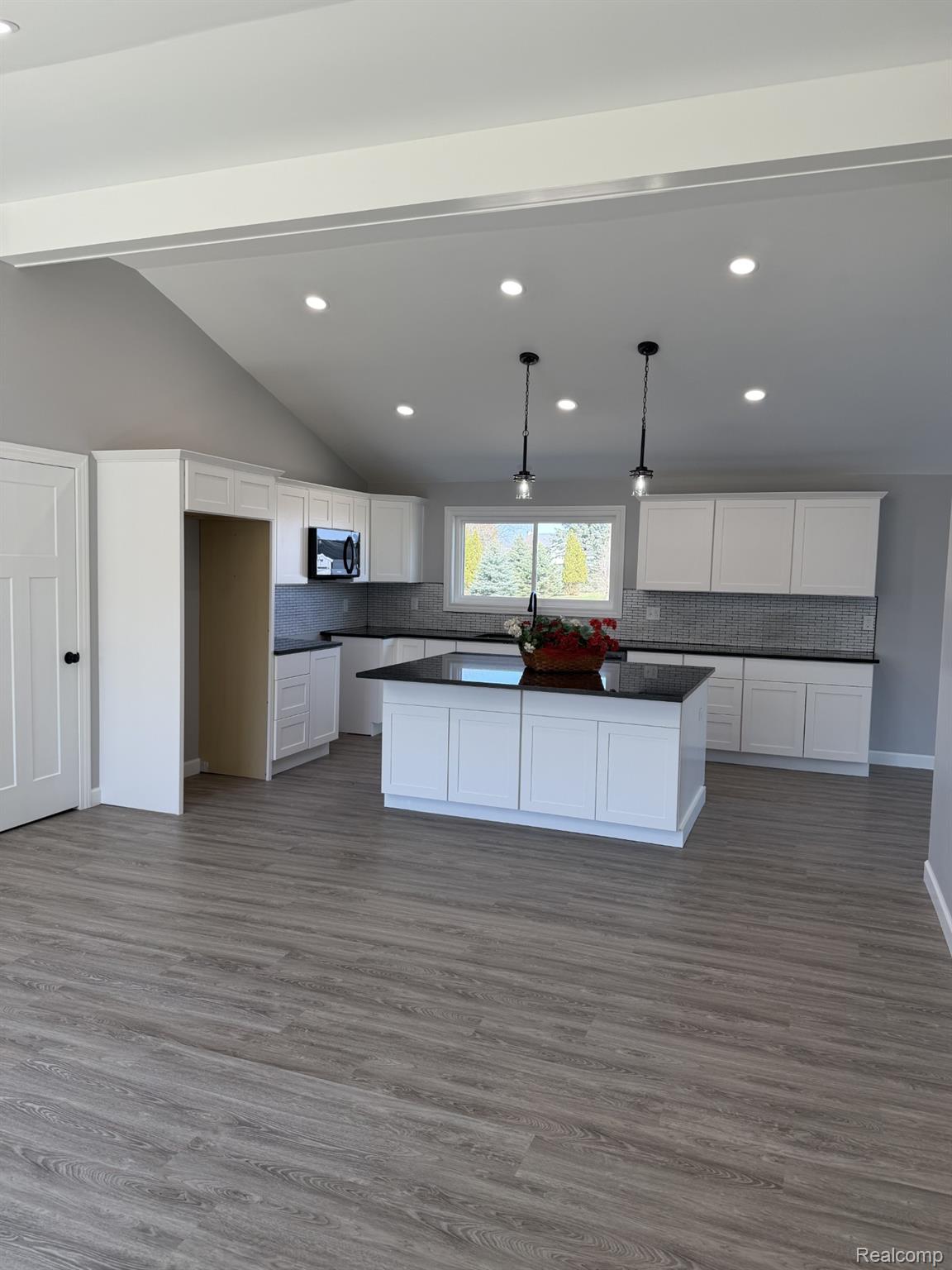 5614 West Marlette Road Marlette, MI 48453 - Photo 7 of 25 Kitchen featuring a center island, dark countertops, white cabinetry, backsplash, and dark wood-style flooring