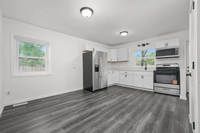 a kitchen with stainless steel appliances a refrigerator cabinets and wooden floor
