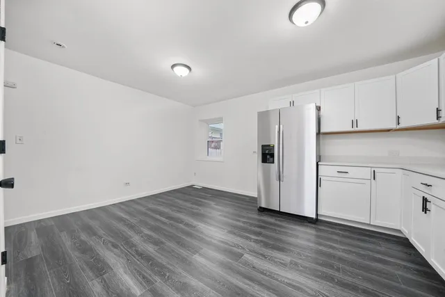 a view of a kitchen with wooden floors and white cabinets