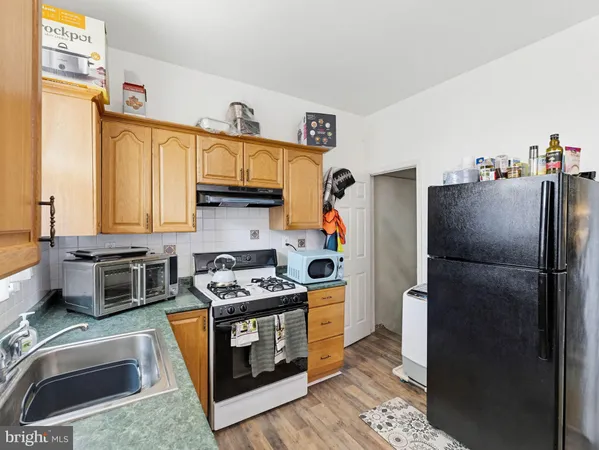 a kitchen with stainless steel appliances granite countertop a refrigerator a stove and a sink with wooden floors