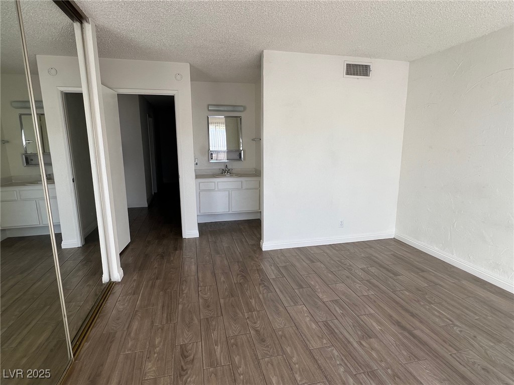 3737 Prosperity Lane Las Vegas, NV 89147 - Photo 6 of 36 Unfurnished bedroom with a textured ceiling, connected bathroom, dark wood-type flooring, and a closet