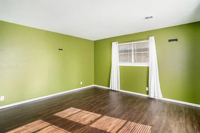 a view of empty room with a window and wooden floor