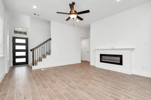 a view of a room with wooden floor and a ceiling fan
