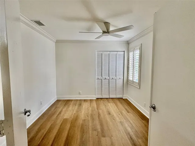 an empty room with wooden floor fan and windows