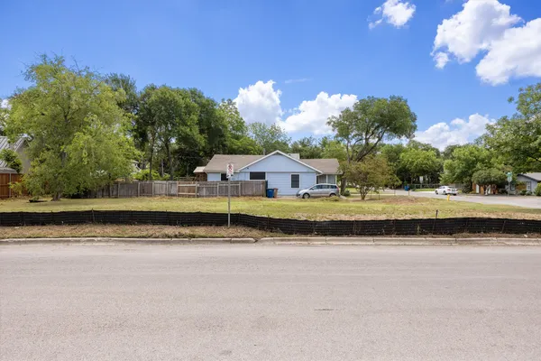 a view of a house with a yard and a large tree