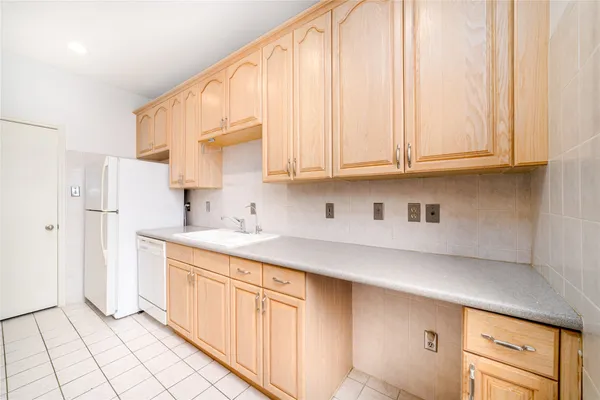 a kitchen with stainless steel appliances granite countertop a sink a refrigerator and white cabinets with wooden floor
