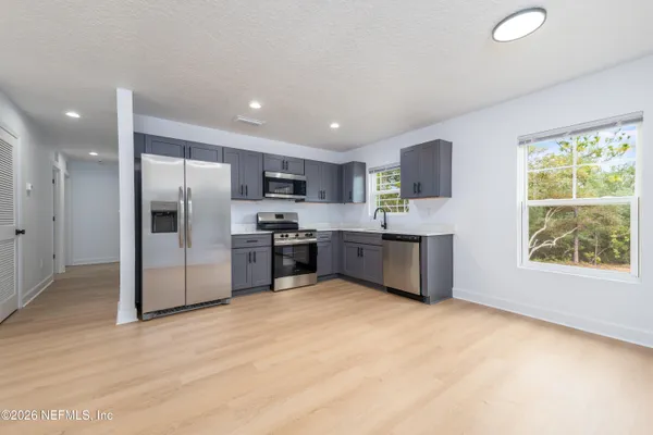 a kitchen with stainless steel appliances kitchen island granite countertop a refrigerator and a sink
