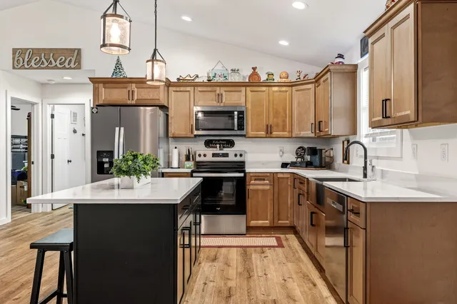 a kitchen with kitchen island granite countertop a sink appliances cabinets and a counter top space