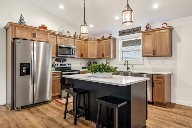 a kitchen with kitchen island granite countertop a sink appliances and cabinets