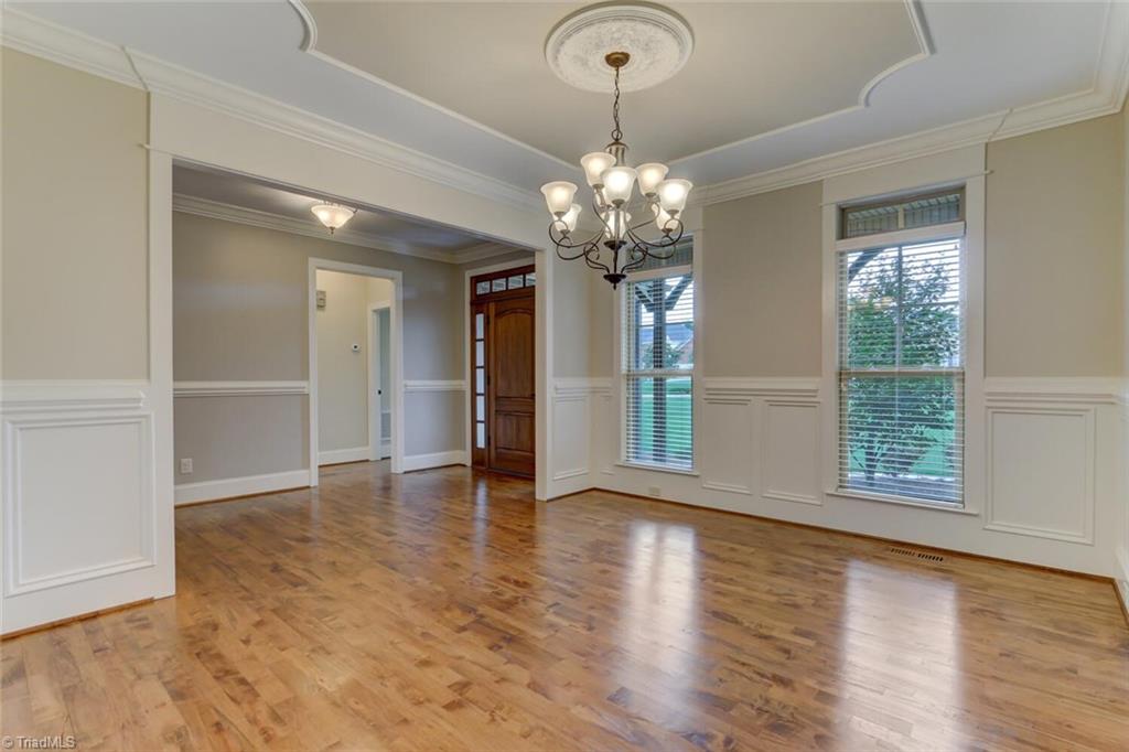 8501 Billet Place Oak Ridge, NC 27310 - Photo 4 of 30 Dining room has extensive moldings for the formal feel you are looking for when entertaining. Also notice the medallion at the light fixture, decorative trim and raised paneled wainscoting.