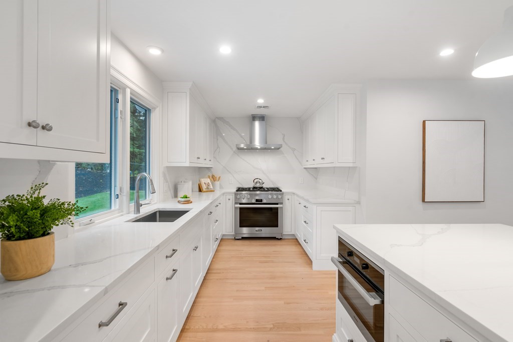 30 Clinton Road Brookline, MA 02445 - Photo 9 of 19 a large white kitchen with stainless steel appliances granite countertop a sink a stove and a refrigerator