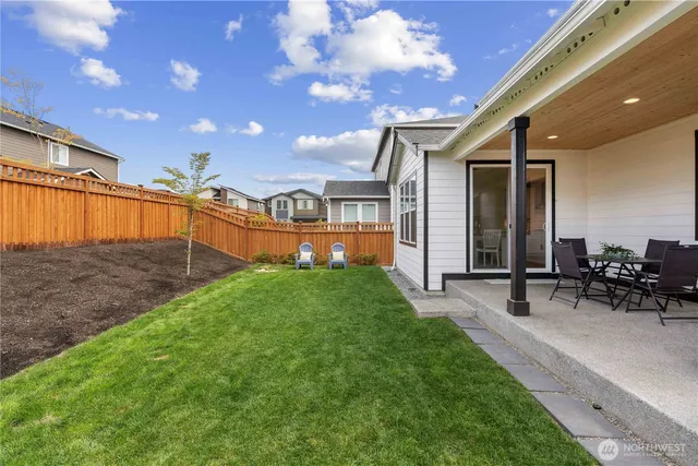 a view of a patio with table and chairs with plants and wooden fence