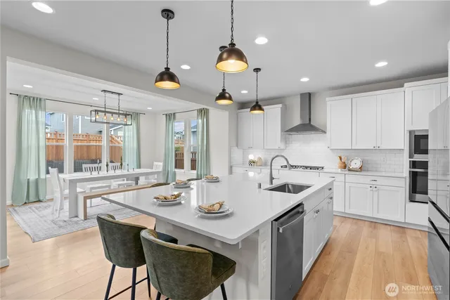 a kitchen with stainless steel appliances granite countertop a sink a stove a dining table and chairs