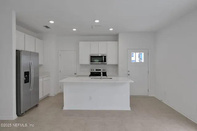 a view of kitchen with kitchen island a refrigerator sink and stove