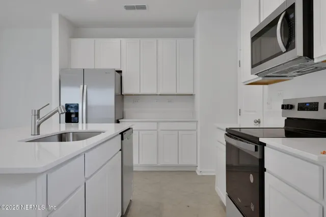 a kitchen with stainless steel appliances granite countertop a sink and a refrigerator