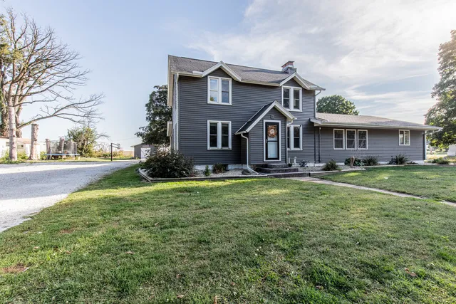 a front view of a house with a garden and trees