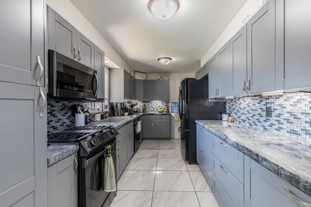 a kitchen with stainless steel appliances granite countertop a stove top oven a sink dishwasher a refrigerator and white cabinets with wooden floor