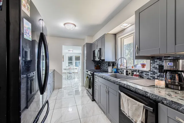 a kitchen with stainless steel appliances granite countertop a refrigerator a stove and a sink