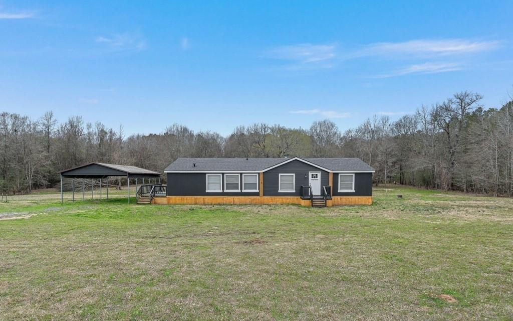 a view of a house with a big yard and large trees