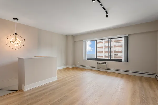 a view of an empty room with a window and wooden floor