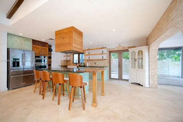 a dining room with stainless steel appliances furniture a large window and a kitchen view