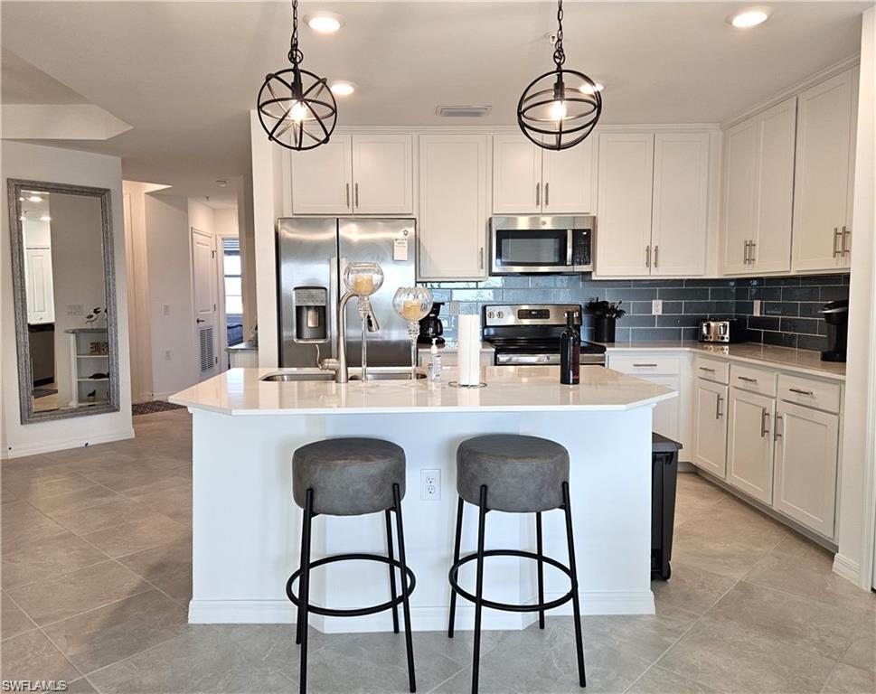 5807 Double Eagle Cir Avenue, Unit 4621 Immokalee, FL 34142 - Photo 6 of 46 Kitchen with decorative backsplash, stainless steel appliances, a center island with sink, a sink, and a breakfast bar area