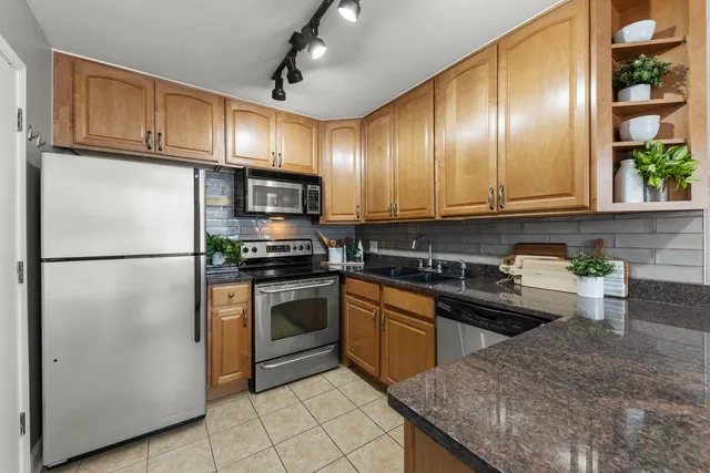 a kitchen with stainless steel appliances granite countertop a stove a refrigerator and a sink