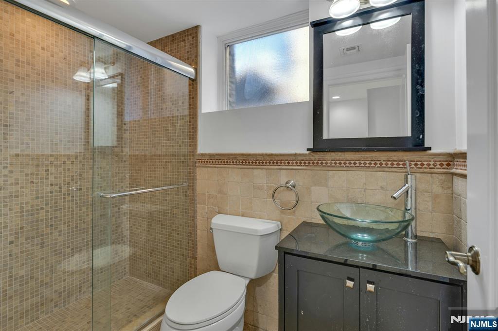 52 Myrtle Avenue, Unit B Edgewater, NJ 07020 - Photo 16 of 20 a bathroom with a granite countertop toilet a sink and mirror