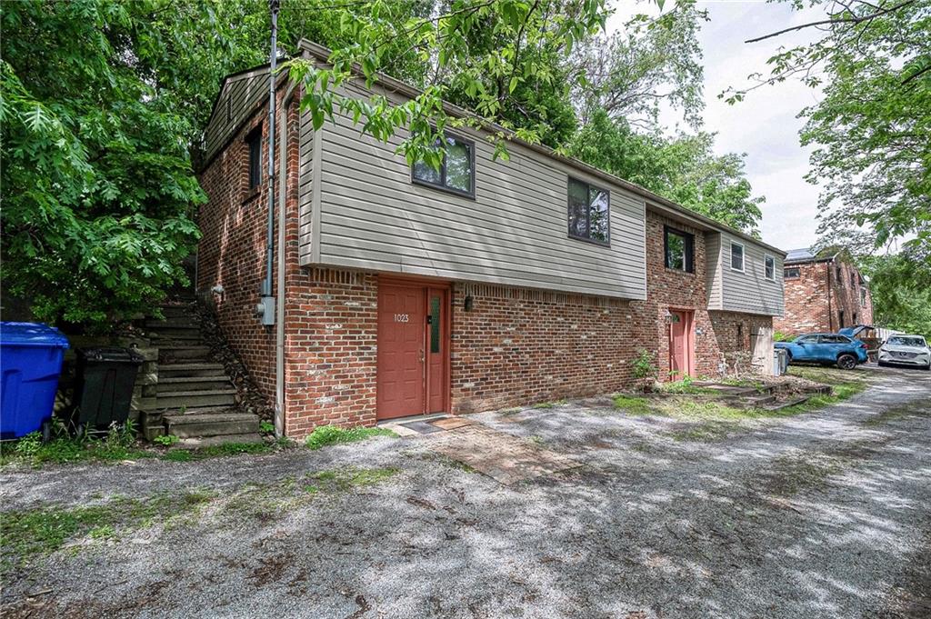 A closer look at the main entrance area for the in-law suite, nestled in a serene, wooded setting. Features a separate concrete staircase leading to the upper-level side yard.