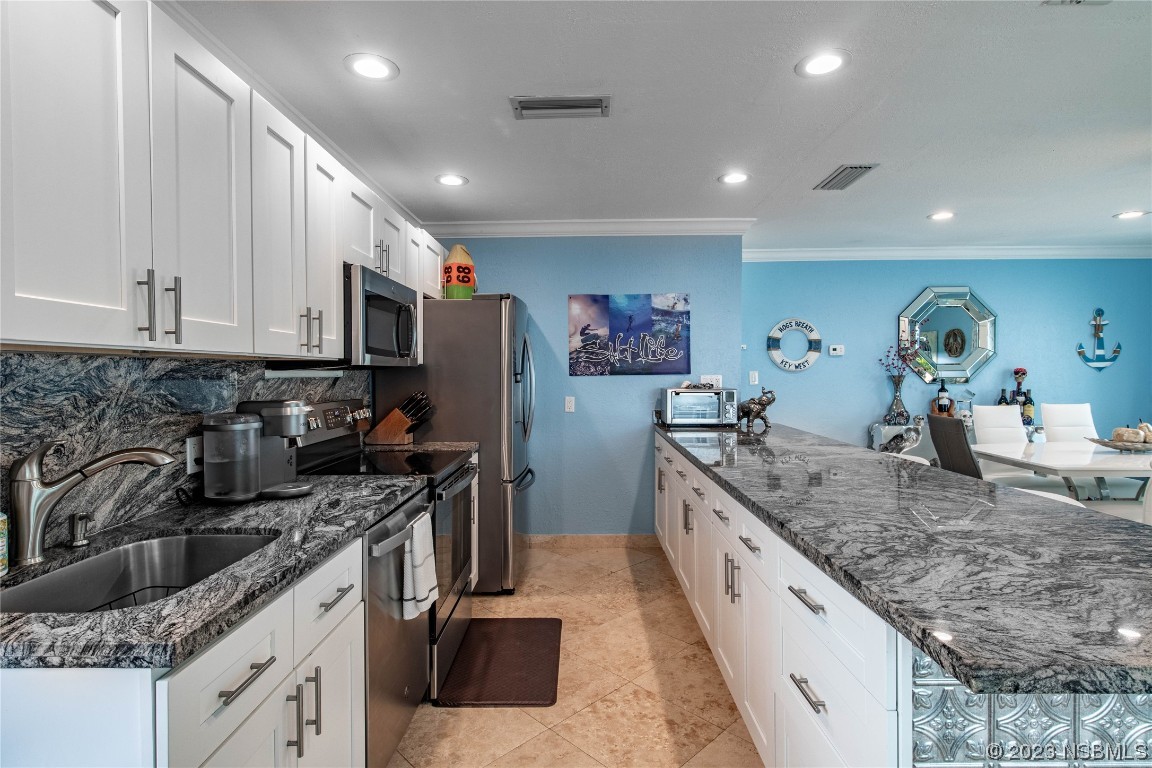 6531 Turtlemound Road New Smyrna Beach, FL 32169 - Photo 10 of 42 a large kitchen with stainless steel appliances granite countertop a sink stove and refrigerator