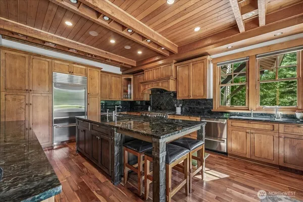 a kitchen with stainless steel appliances granite countertop a stove a sink and wooden cabinets