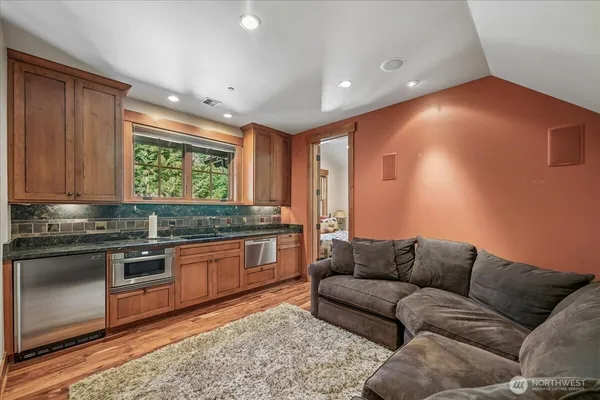 a living room with stainless steel appliances granite countertop furniture and a wooden floor
