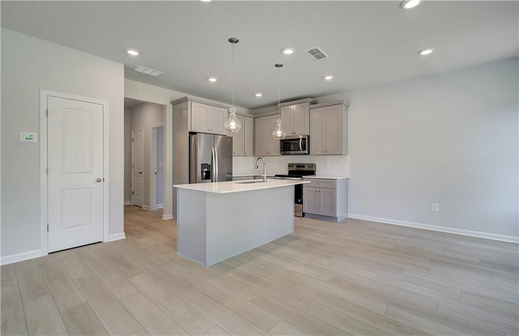 117 Alpine Road Fairburn, GA 30213 - Photo 10 of 29 a large kitchen with stainless steel appliances a large counter top and wooden floors