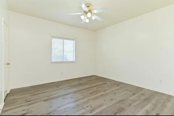 an empty room with a window and a fan