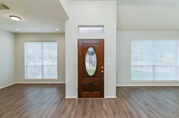 an empty room with wooden floor wooden cabinet and windows