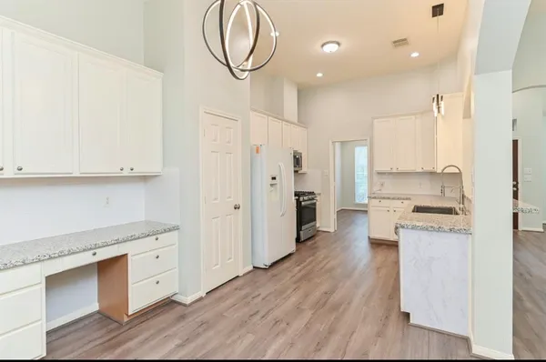 a kitchen with stainless steel appliances a stove top oven a sink a refrigerator white cabinets and wooden floor