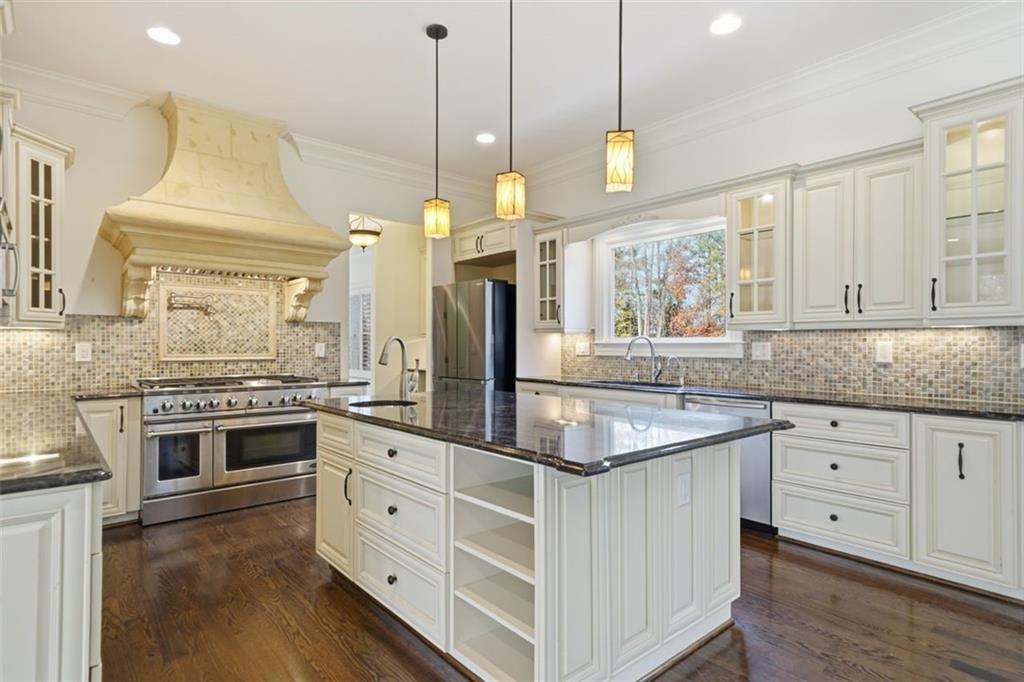 7611 Regency Circle Sandy Springs, GA 30350 - Photo 13 of 74 a kitchen with stainless steel appliances granite countertop a stove a sink and a chandelier