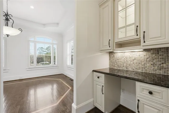an empty room with wooden floor ceiling fan and windows