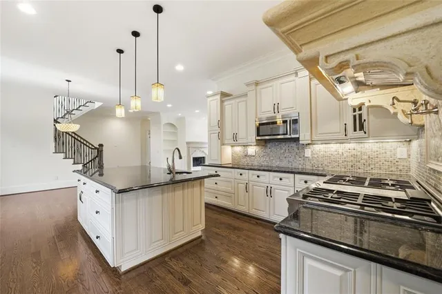 a kitchen with stainless steel appliances granite countertop a stove a sink and a chandelier