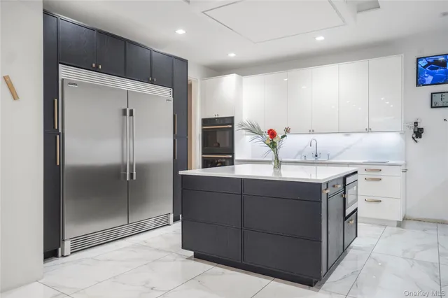 a kitchen with kitchen island granite countertop a refrigerator and a sink