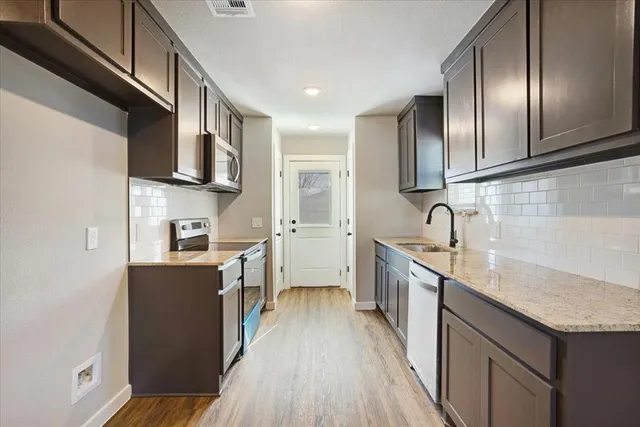 a kitchen with stainless steel appliances granite countertop a sink stove and refrigerator