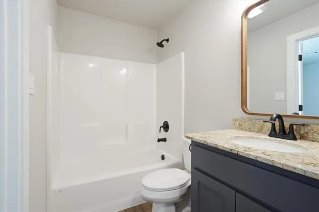 a bathroom with a granite countertop sink a toilet and a mirror