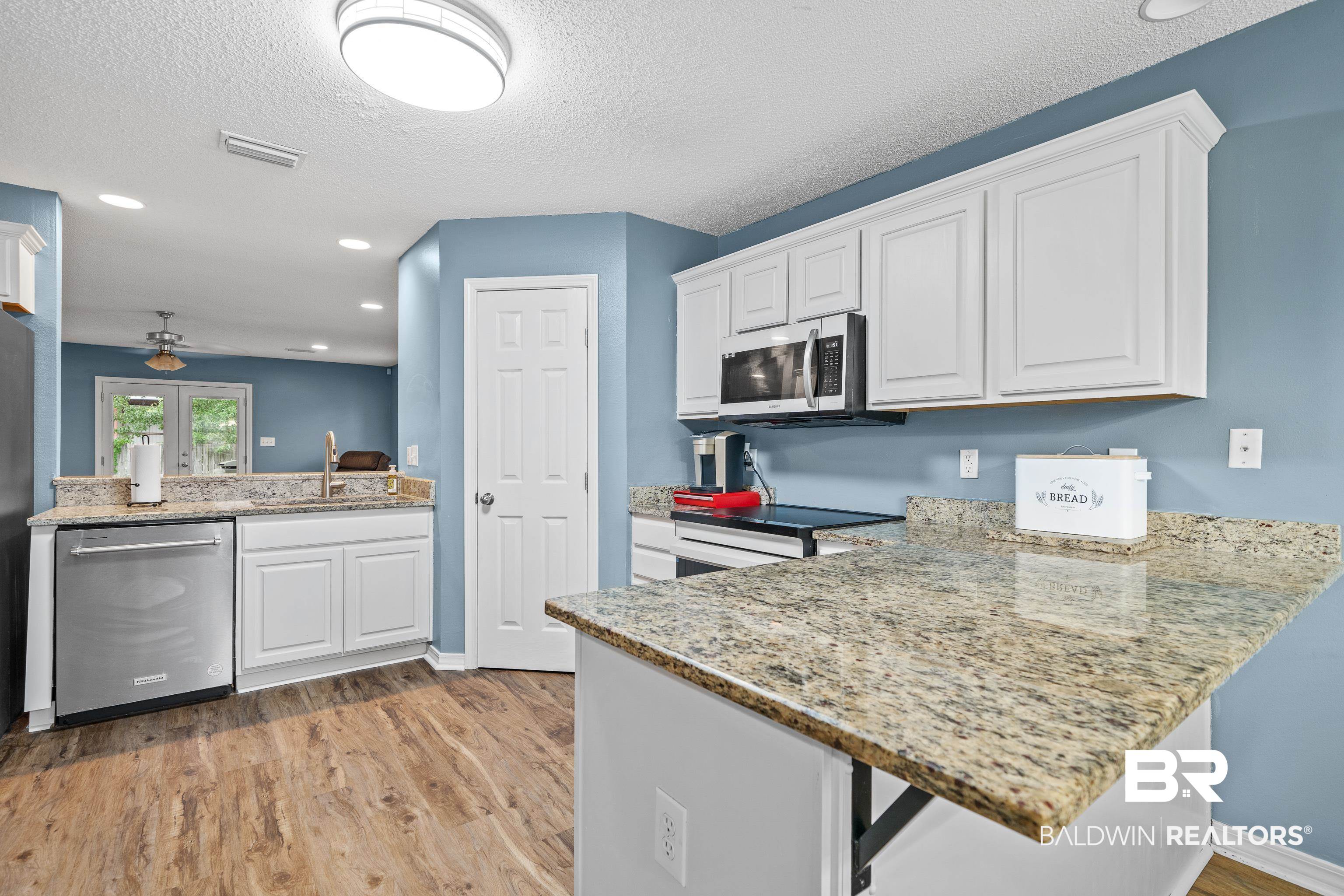 9552 Collier Loop Daphne, AL 36526 - Photo 7 of 28 Kitchen featuring stainless steel appliances, light wood-type flooring, a sink, white cabinetry, and a textured ceiling