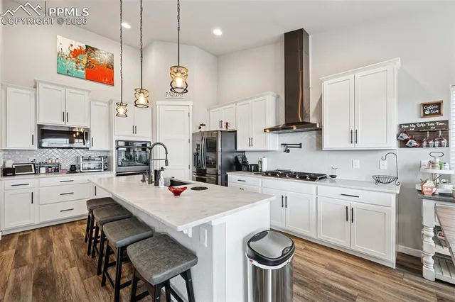 a kitchen with stainless steel appliances a stove a sink dishwasher and a refrigerator with wooden floor