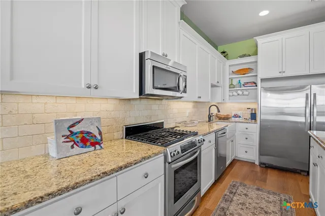 a kitchen with stainless steel appliances granite countertop a sink stove and cabinets