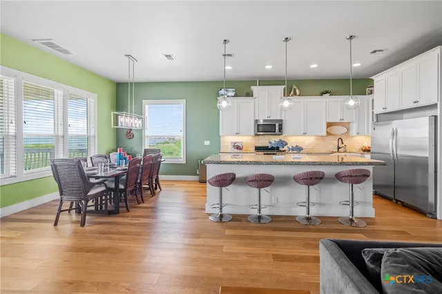 a kitchen with stainless steel appliances kitchen island granite countertop a table chairs and a refrigerator