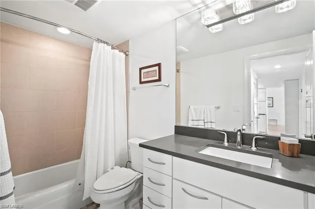 a bathroom with a granite countertop sink a toilet a mirror a vanity and shower